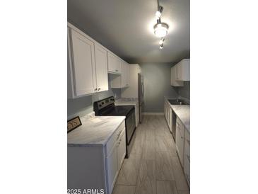 Well-lit kitchen featuring white cabinets, marble countertops, and stainless steel appliances at 2121 W Royal Palm Rd # 1014, Phoenix, AZ 85021