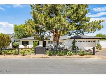 Charming single-story home with a well-manicured front yard, black fence and lush landscaping at 3308 N 51St St, Phoenix, AZ 85018