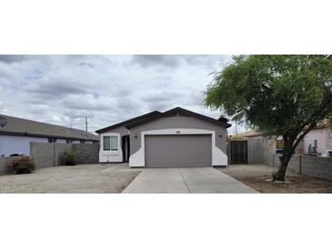 Charming home featuring a two-car garage, desert landscaping, and a cozy covered entry at 719 E Broadway Ave, Apache Junction, AZ 85119