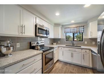 Bright kitchen with stainless steel appliances, white cabinets, and gray subway tile backsplash at 750 E Northern Ave # 2143, Phoenix, AZ 85020