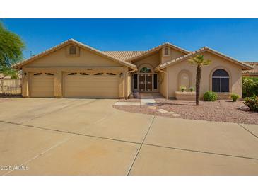 Charming tan home featuring a three-car garage and desert landscaping at 8627 W Morrow Dr, Peoria, AZ 85382