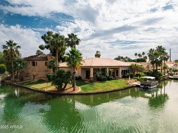 Waterfront home with tile roof, lush landscaping, and a boat dock for enjoying the serene lake at 2128 E Clipper Ln, Gilbert, AZ 85234