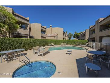 Community pool area with lounge chairs, tables, and manicured hedges in a well-maintained complex at 2228 N 52 St # 213, Phoenix, AZ 85008