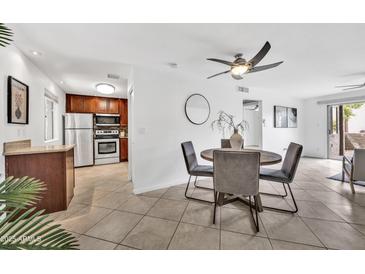 Bright dining area with a modern ceiling fan, adjacent to an updated kitchen and sliding glass doors to the patio at 4354 N 82Nd St # 167, Scottsdale, AZ 85251
