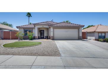 Charming single-story home with desert landscaping, a tiled roof, and a two-car garage at 10557 W Louise Dr, Peoria, AZ 85383