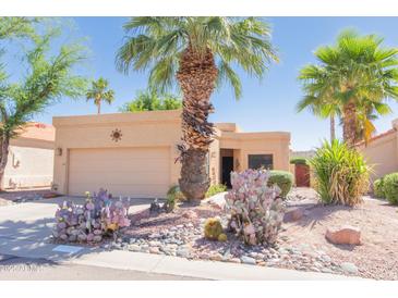 Charming tan home featuring desert landscaping, vibrant cacti, and a mature palm tree at 17342 E Quail Ridge Dr, Fountain Hills, AZ 85268