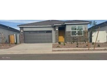 Charming single-story home featuring a gray exterior, gray garage door, and low maintenance landscaping at 25235 N 183Rd Dr, Wittmann, AZ 85361