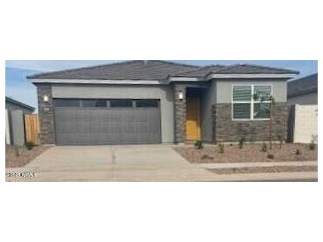 Charming single-story home featuring a gray exterior, gray garage door, and low maintenance landscaping at 25235 N 183Rd Dr, Wittmann, AZ 85361