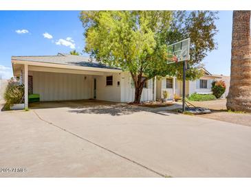 Charming single-story home featuring a large carport, basketball hoop, and lush landscaping at 7424 E Cambridge Ave, Scottsdale, AZ 85257