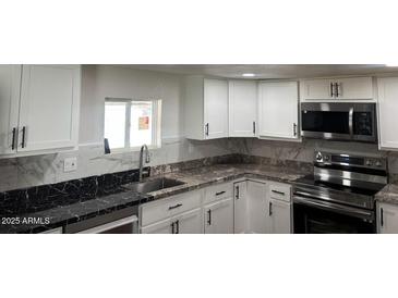 Modern kitchen featuring white cabinets, stainless steel appliances, and granite countertops at 2721 E Beverly Ln, Phoenix, AZ 85032