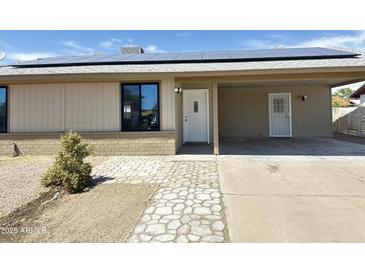 Charming single-story home featuring a solar-paneled roof and a welcoming front entrance with stone pathway at 5924 W Tierra Buena Ln, Glendale, AZ 85306