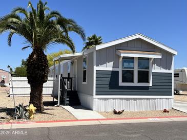 Charming manufactured home with blue and gray siding, complemented by a beautiful mature palm tree at 625 W Mckellips Rd # 111, Mesa, AZ 85201