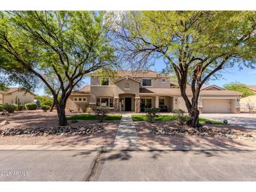 Two-story home with a landscaped front yard and mature trees in a desert landscape at 9998 W Prospector Dr, Queen Creek, AZ 85144