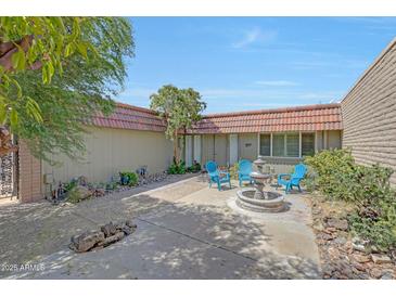 Inviting courtyard featuring a charming water fountain and a small sitting area with blue Adirondack chairs at 13806 N Del Webb Blvd, Sun City, AZ 85351
