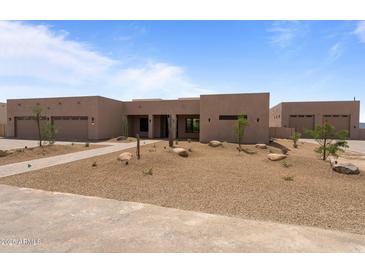 A stunning, desert-landscaped single-story home features a clean modern aesthetic and three-car garage at 39302 N 30Th Dr, Phoenix, AZ 85086