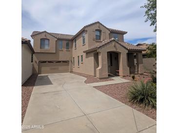 Two-story home with neutral-toned exterior, desert landscaping, and wide driveway leading to a two-car garage at 15446 W Jenan Dr, Surprise, AZ 85379