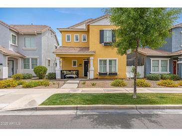 Charming two-story home featuring a yellow facade, manicured landscaping, and a welcoming front porch with seating at 1316 S Minneola Ln, Gilbert, AZ 85296