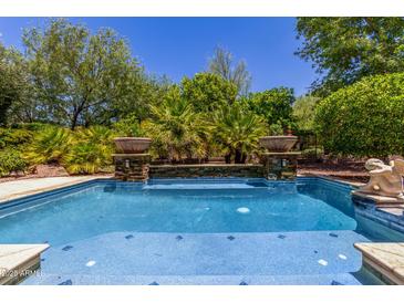 A pristine pool with tile detail, potted plants and privacy landscaping offers a backyard oasis at 30135 N 129Th Gln, Peoria, AZ 85383