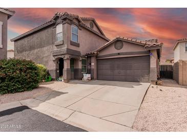 Inviting two-story home with a two-car garage and neutral colored stucco facade, set against a fiery sunset backdrop at 3488 S Bowman Rd, Apache Junction, AZ 85119