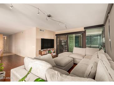 Spacious living room featuring a large sectional sofa, wood floors, and sliding glass doors to the outside at 4808 N 24Th St # 204, Phoenix, AZ 85016