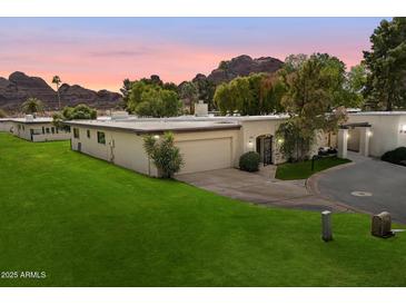 Charming single-story home with a well-manicured lawn and desert landscaping, set against a backdrop of mountains at 6055 E Vernon Ave, Scottsdale, AZ 85257