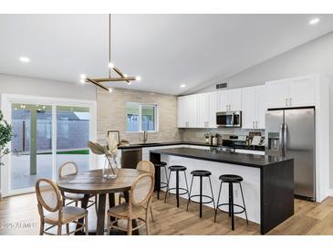 Modern kitchen boasts stainless steel appliances, a black countertop island, and adjacent dining area at 6441 E Julep St, Mesa, AZ 85205