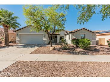 Charming single-story home featuring a well-manicured yard, two-car garage, and desert landscaping at 13630 W Redfield Rd, Surprise, AZ 85379