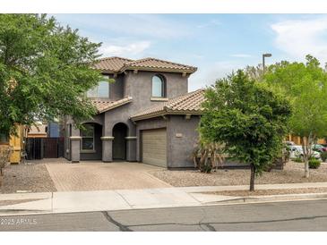 Charming two-story home featuring a tile roof, arched entryway, and a well-manicured front yard with mature trees at 3952 E Frances Ln, Gilbert, AZ 85295