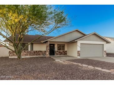 Charming single-story home featuring a desert landscape, two-car garage, and stone accents at 6244 E Inglewood St, Mesa, AZ 85205
