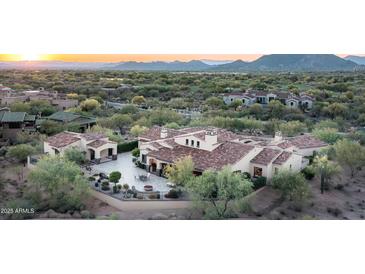 Expansive desert home featuring an outdoor living space, fire pit, lush landscaping, and mountain views at 7753 E Whisper Rock Trl, Scottsdale, AZ 85266