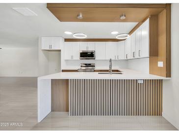 Modern kitchen with white cabinets, stainless steel appliances, and a stylish waterfall countertop at 8146 N 17Th Dr, Phoenix, AZ 85021