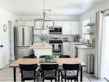 Bright kitchen boasts stainless steel appliances, white cabinetry, and a stylish island with light wood counter at 1469 S Boulder St # C, Gilbert, AZ 85296