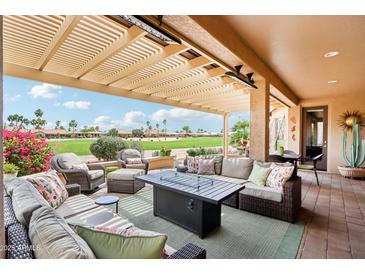 Inviting covered patio with wicker furniture and a cozy fireplace, perfect for outdoor gatherings and enjoying the golf course view at 16077 W Vale Dr, Goodyear, AZ 85395