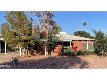 Charming single-story brick home with a well-maintained front yard, mature trees, and red rock landscaping at 3115 N 26Th St, Phoenix, AZ 85016
