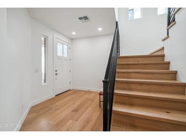 Inviting entryway featuring light wood floors, white walls, and a modern staircase with a black railing at 5537 E Earll Dr, Phoenix, AZ 85018