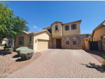 Charming two-story home featuring stone accents, a two-car garage, and a brick-paved driveway at 5635 W Huntington Dr, Laveen, AZ 85339