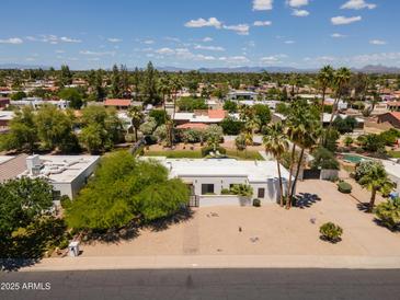 Expansive aerial view of a modern white home with desert landscaping, a gated entry, and distant mountain views at 6102 E Friess Dr, Scottsdale, AZ 85254