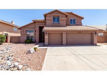 Two-story home with a red tile roof, three-car garage and low-maintenance desert landscaping at 7179 W Surrey Ave, Peoria, AZ 85381