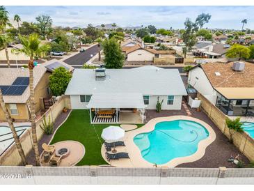 Aerial view of a backyard featuring a pool, covered patio with table, and fire pit with lounge chairs at 19414 N 3Rd Ave, Phoenix, AZ 85027