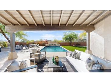 Inviting covered patio with comfortable seating overlooking the sparkling pool and lush backyard at 9669 E Chino Dr, Scottsdale, AZ 85255
