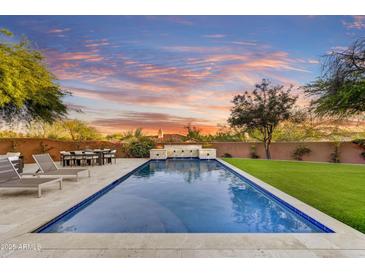 Inviting pool with sleek stone accents, lush landscaping, and relaxing lounge chairs under a beautiful Arizona sunset at 9669 E Chino Dr, Scottsdale, AZ 85255