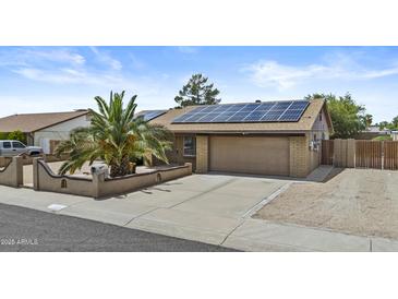 Charming home featuring solar panels, a two-car garage, and a lovely front yard with a palm tree at 17244 N 29Th Ave, Phoenix, AZ 85053