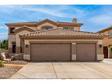 Traditional two-story home with a large three car garage and desert landscaping in the front at 5993 W Topeka Dr, Glendale, AZ 85308