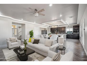 Bright living room with modern furnishings that flows into the kitchen with dark wood cabinets at 1712 E Joelle Dr, Casa Grande, AZ 85122