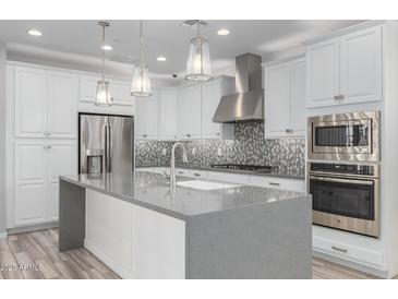 Modern kitchen with stainless steel appliances, large island and mosaic tile backsplash at 1848 S Follett Way, Gilbert, AZ 85295