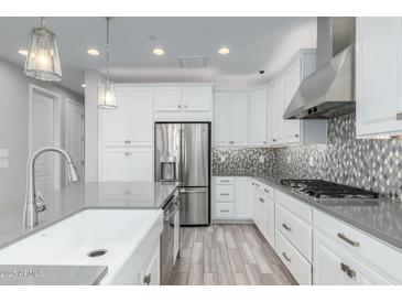 Modern kitchen featuring white cabinets, stainless steel appliances, and a stylish backsplash at 1848 S Follett Way, Gilbert, AZ 85295