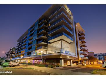 Modern condo building with glass balconies and manicured landscaping under a dramatic evening sky at 4422 N 75Th St # 8004, Scottsdale, AZ 85251