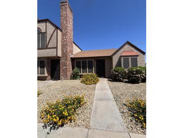 Charming townhome with manicured gravel yard, vibrant yellow flowers, and a brick chimney at 7905 W Thunderbird Rd # 305, Peoria, AZ 85381
