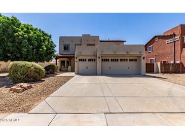 Beige two-story home featuring a three-car garage and low-maintenance desert landscaping at 15683 W Minnezona Ave, Goodyear, AZ 85395