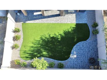 Aerial view of a backyard featuring an artificial turf lawn, paver patio, and desert landscaping at 20217 W Desert Bloom St, Buckeye, AZ 85326